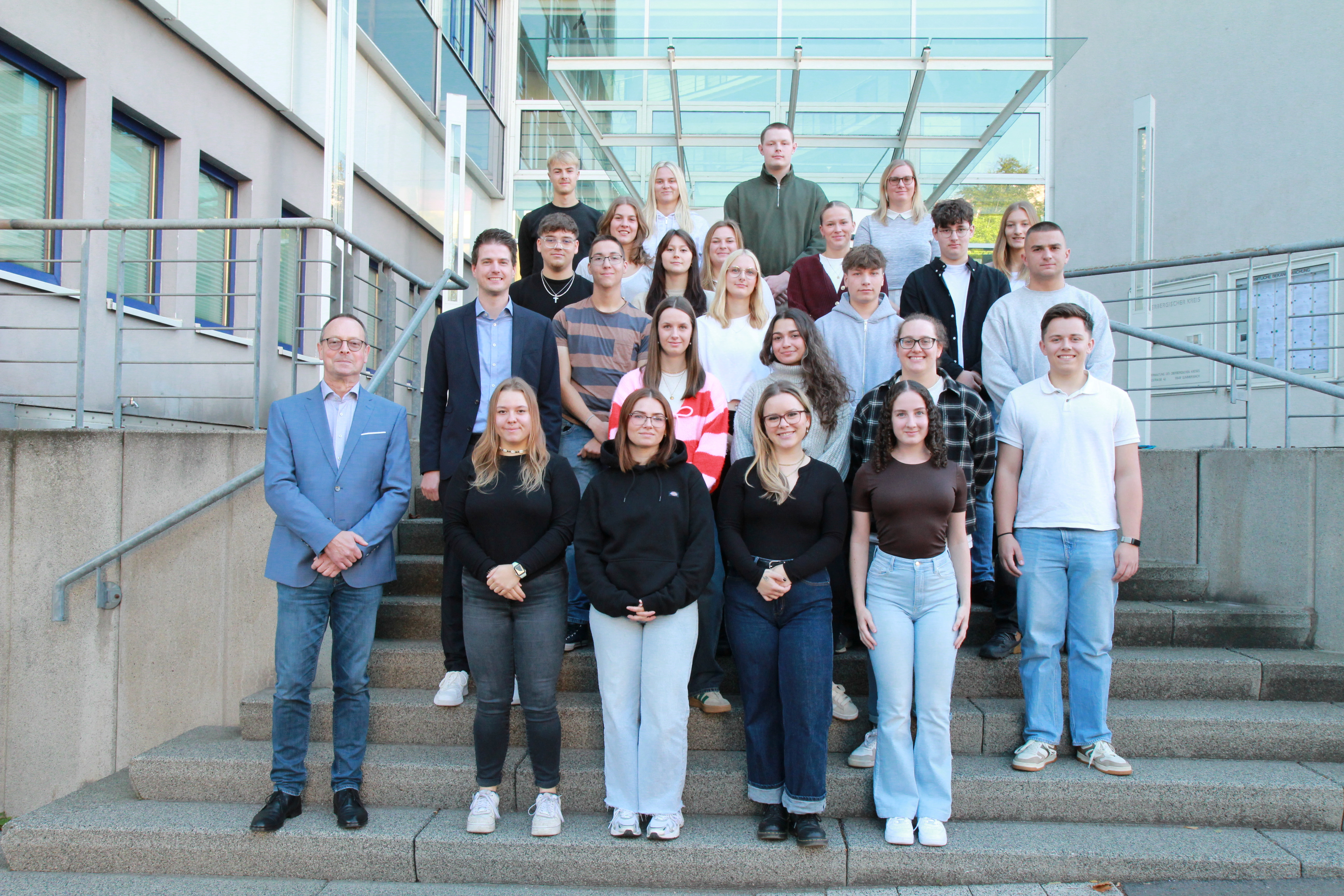 Foto: OBK Eine Gruppe von Menschen steht auf einer Treppe vor einer Glasfassade.