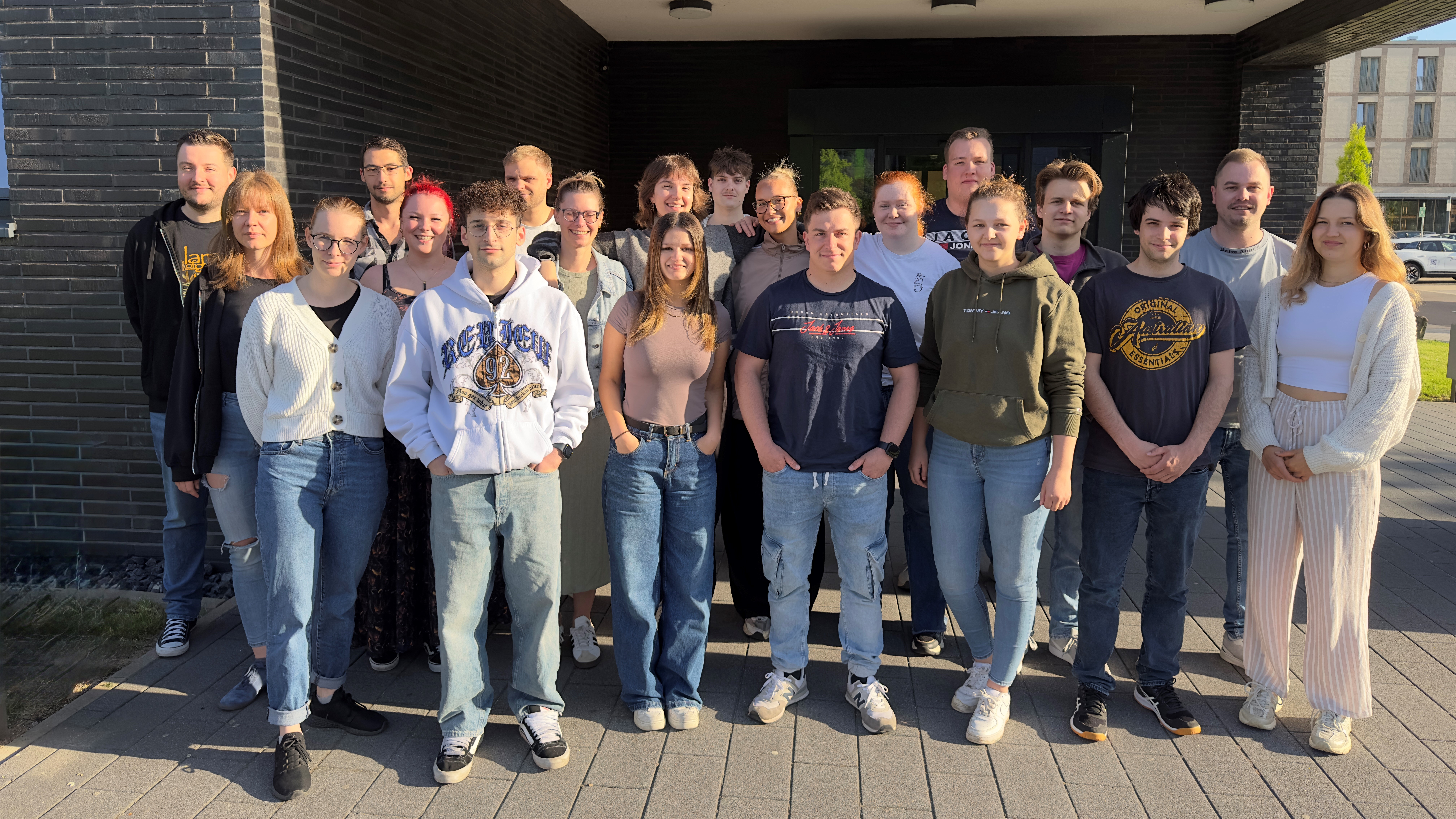 Eine Gruppe junger Menschen steht vor der Akademie Gesundheitswirtschaft und Senioren.